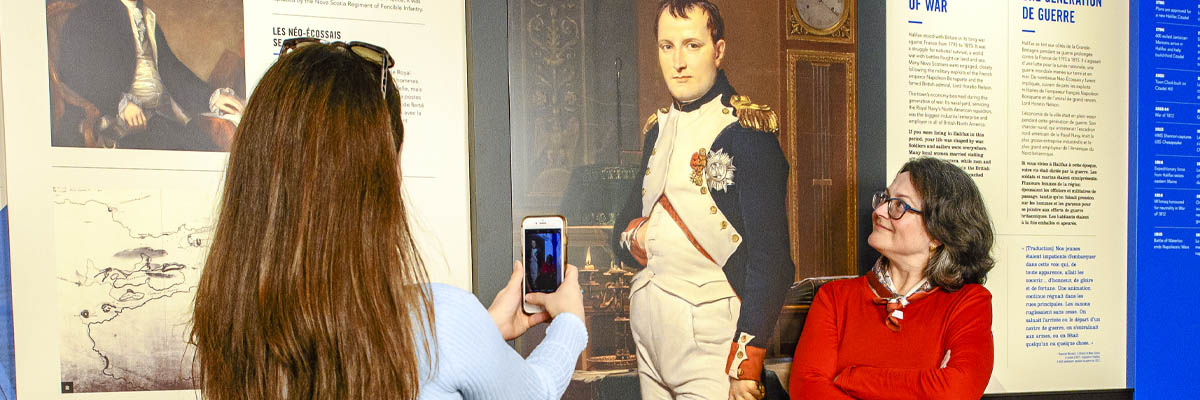 Visiteurs se prenant en photo avec un portrait grandeur nature de Napoléon