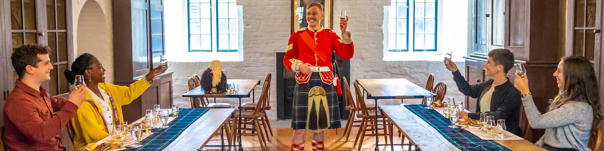 Des personnes assises aux tables ornementées lèvent leur verre pour faire un toast.  