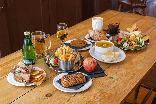 Une variété de plats et de boissons, dont de l’alcool, du café, de la salade, de la soupe, des sandwiches, des frites et des pâtisseries.