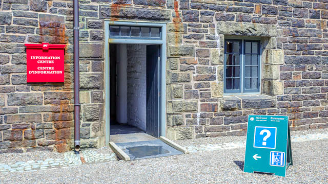 Une petite rampe au-dessus d'un fossé de drainage menant à un bâtiment en pierre.