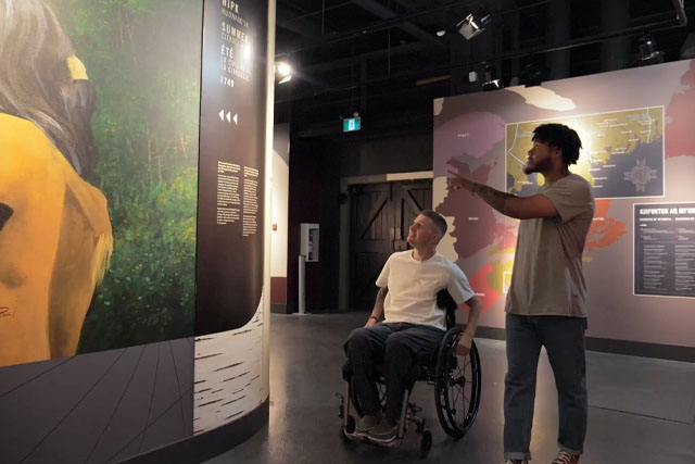 Deux visiteurs regardent de grandes expositions accrochées aux murs du sol au plafond.