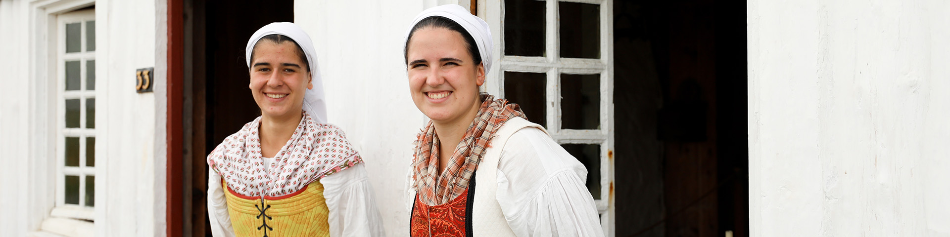 Deux femmes sourient à la caméra en portant des costumes traditionnels basques.