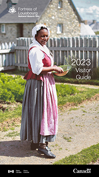 Cover of the Fortress of Louisbourg National Historic Site visitor guide 2023  which shows a woman dressed in 18th century costume stands in a garden and looks at the camera