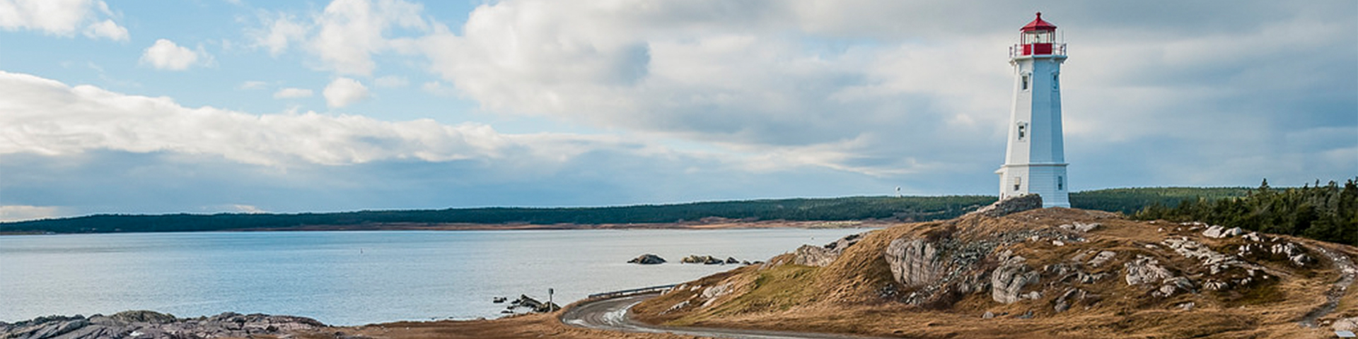 Un phare sur une falaise rocheuse surplombant l'océan en direction du Lieu historique national de la Forteresse-de-Louisbourg. 