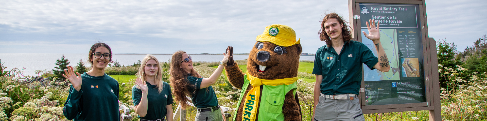 Four members of the Parks Canada outreach team wave and high five the mascot Parka.