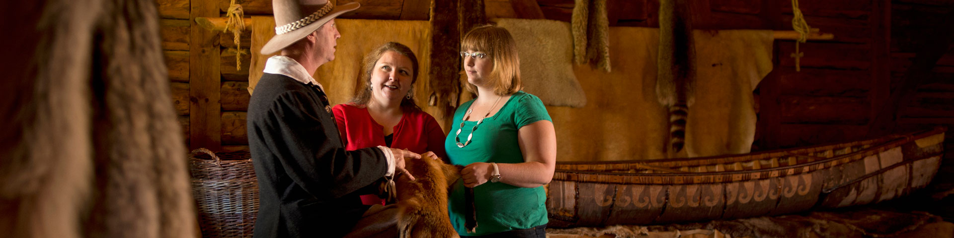 Visitors talk with a costumed interpreter in the fur trade room. 