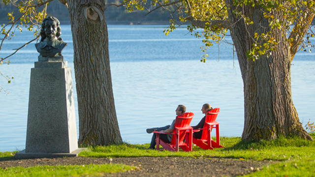 Visitors enjoying the view of the river from the red chairs.