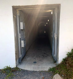 Vue sur un tunnel étroit à travers une porte métallique.