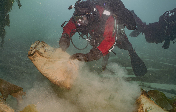 Scuba diver picking coat up off the seafloor