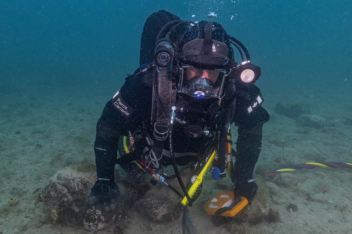 Parks Canada underwater archaeology technician Joe Boucher examines one of HMS Erebus’ ice anchors discovered in 2023 within the debris field surrounding the hull, September 13, 2023.