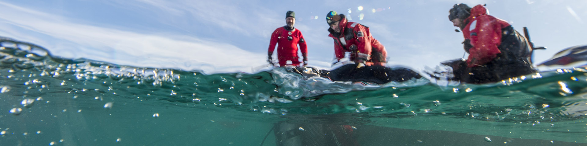 Three underwater archaeologists looking into the water. 