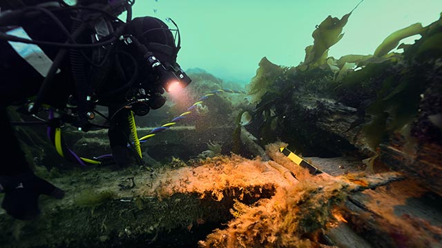 Parks Canada Underwater Archaeologist examines a belaying pin on the upper deck of HMS Erebus, September 2022.