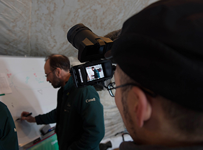 A Parks Canada underwater archaeologist writing on a white board while being filmed.