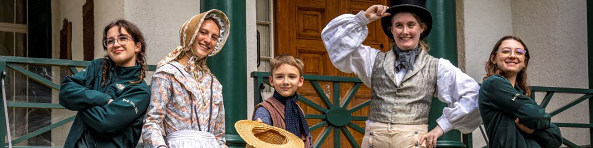 Un groupe en uniformes et costumes se tient devant une maison historique.