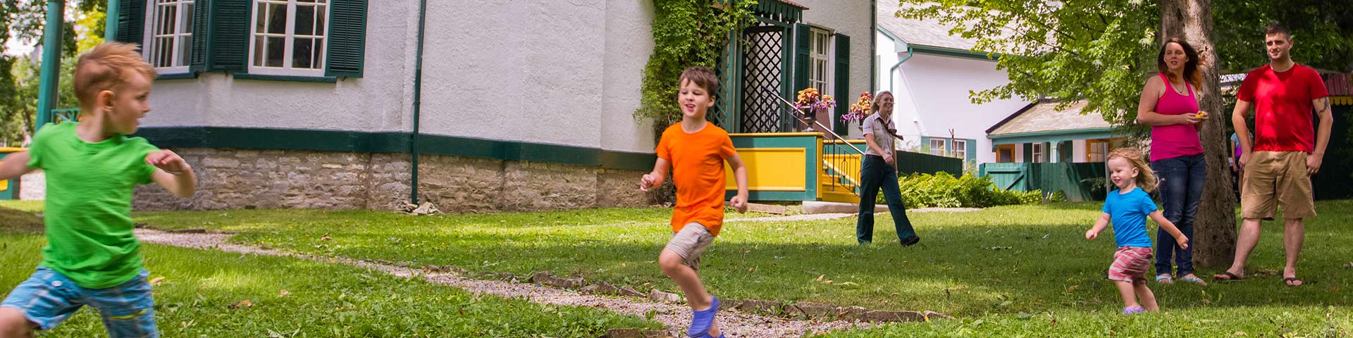 A family plays outside a historic house.