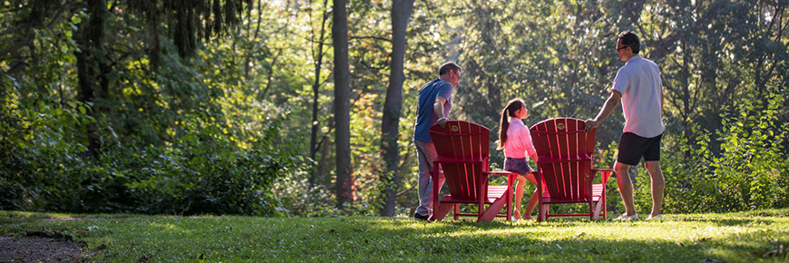 Une famille debout à côté de chaises rouges.