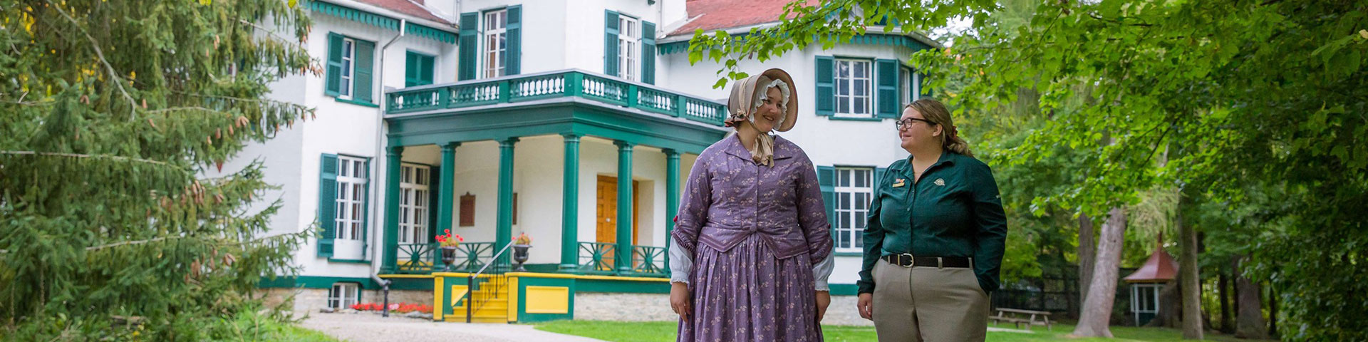 Deux employés se tiennent devant la maison historique.