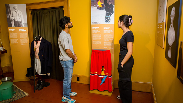 Two visitors look at a display with a brightly coloured skirt. 