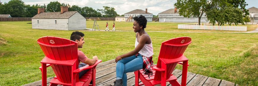 Un jeune couple relaxant dans les chaises rouges, lieu historique national du Fort-George.