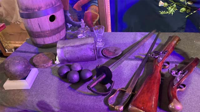 Une collection d'armes diverses du 18e siècle exposée sur une table lors d'un événement historique.