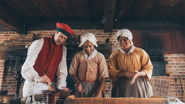 Three heritage presenters in historic dress bake in the historic cookhouse