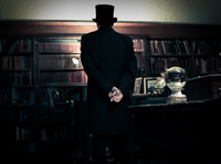 dark figure stands infront of a book shelf