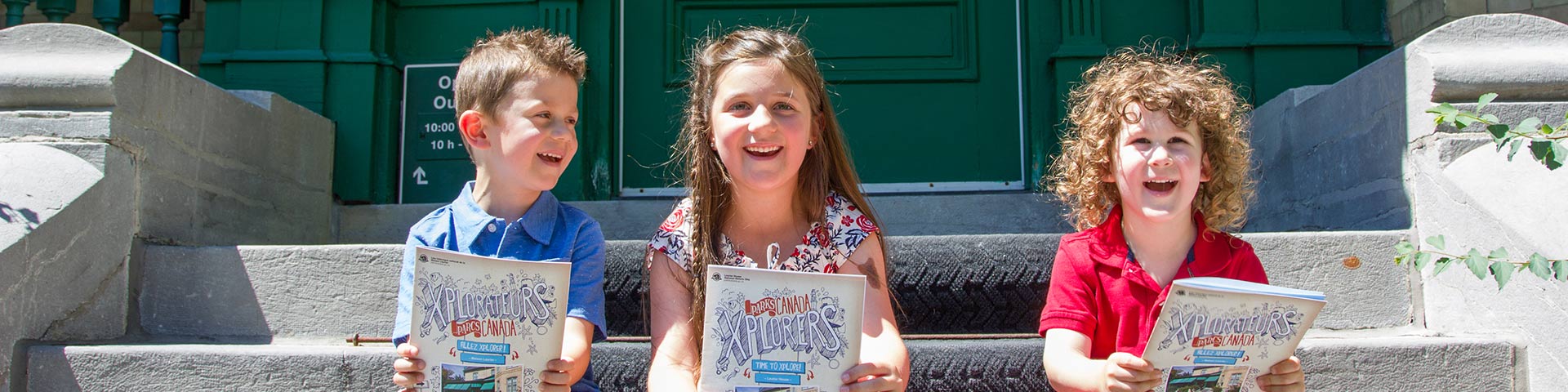 Kids sit on some steps with a workbook.