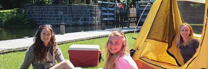 Three women enjoy camping at a Rideau Canal lockstation.