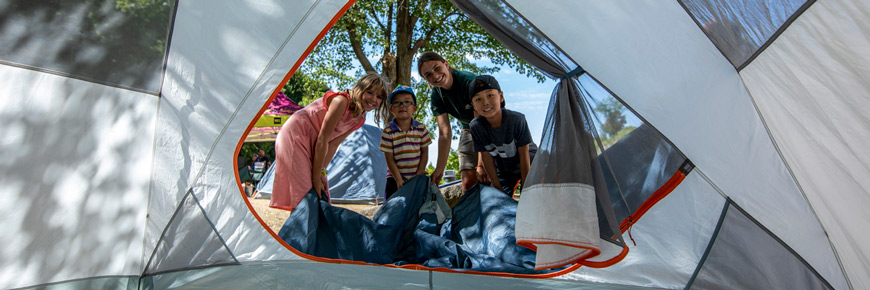 Des enfants apprennent comment monter une tente dans le cadre d'une activité d'initiation au camping le long du canal Rideau