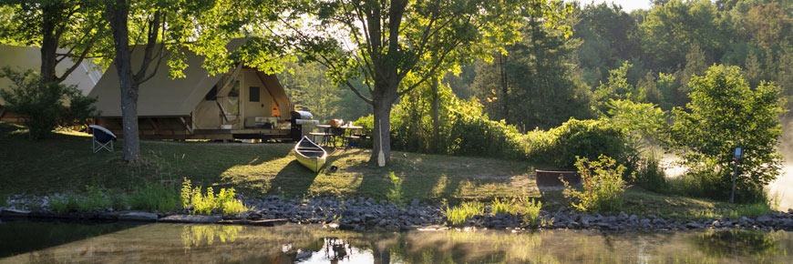 An oTENTik campsite with a canoe beside the water