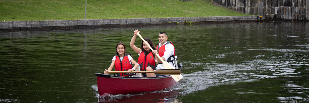 A dad and his young daughters paddle away from a lock