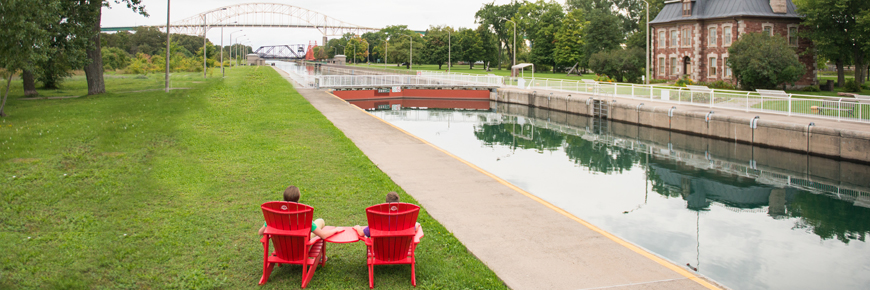 Two red chairs beside the canal.