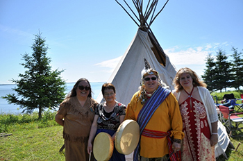 Four people in front of a tiipii