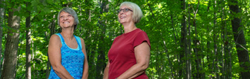 Two women standing in a forest.