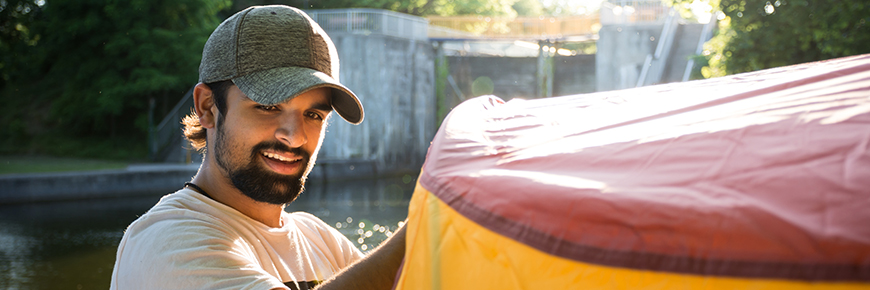 A camper sets up their tent in front of a Trent-Severn Waterway lock.