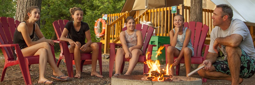 A family sitting around a campfire outside of oTENTik