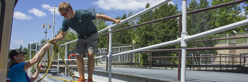 Un élève de Parcs Canada aidant un plaisancier à un poste d'écluasage.