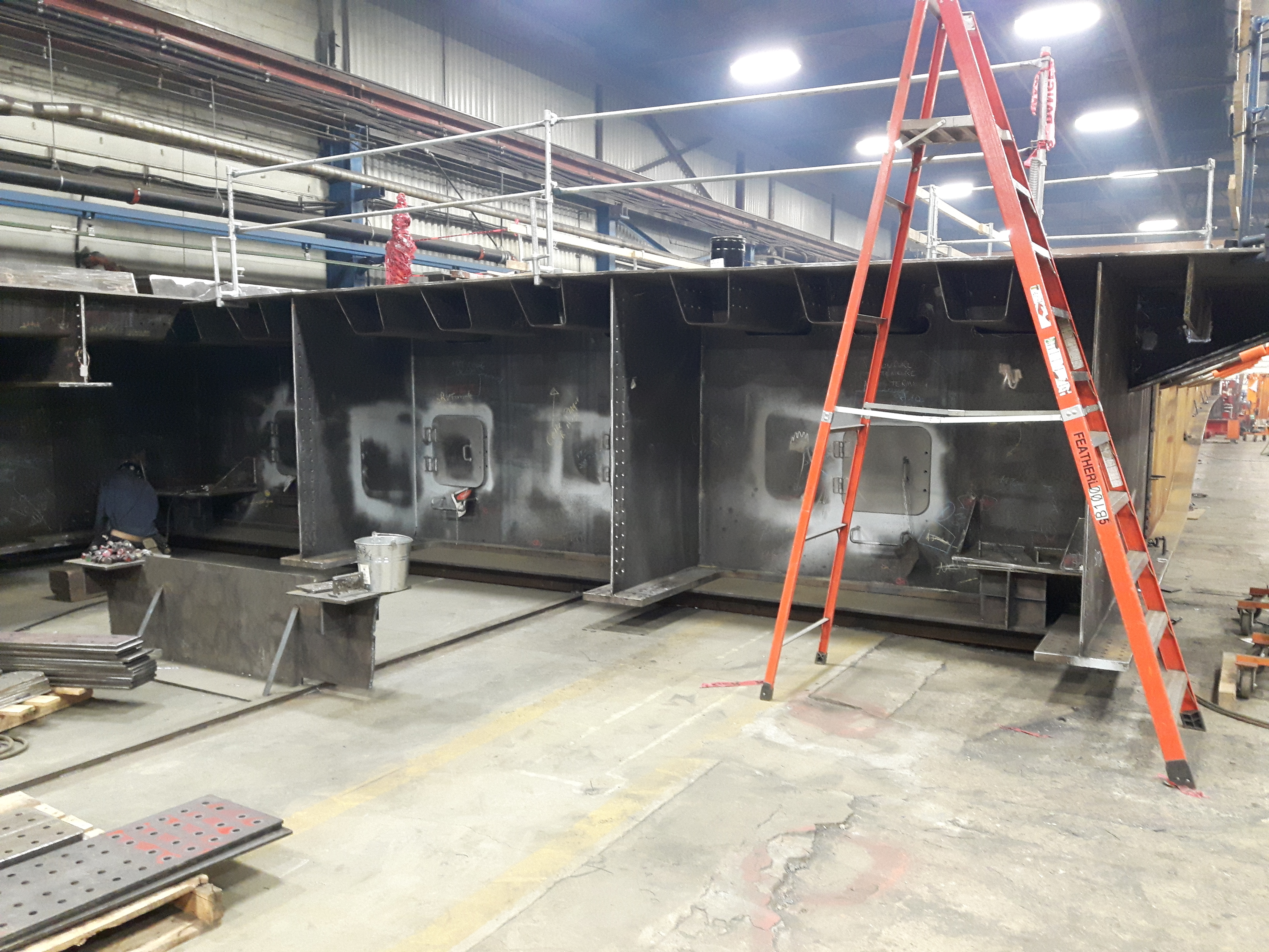 A large section of steel is being fabricated in a machine shop.