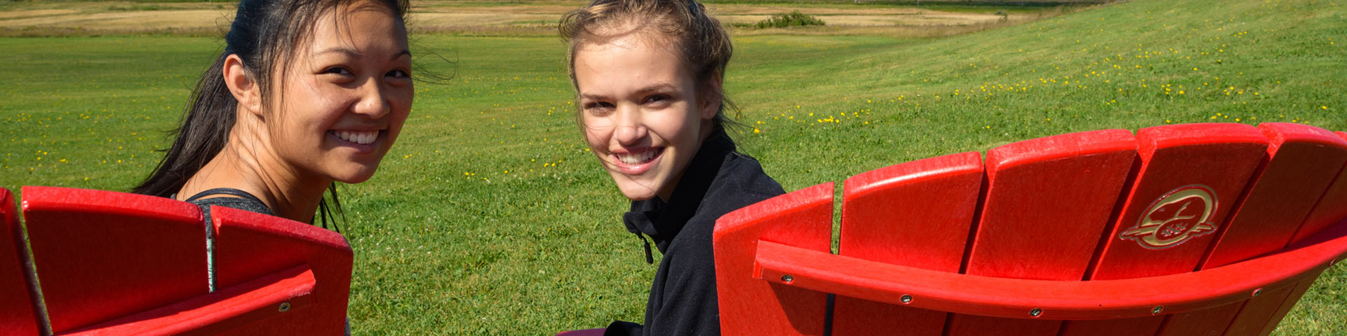 Deux visiteurs sourient assis sur des chaises rouges.