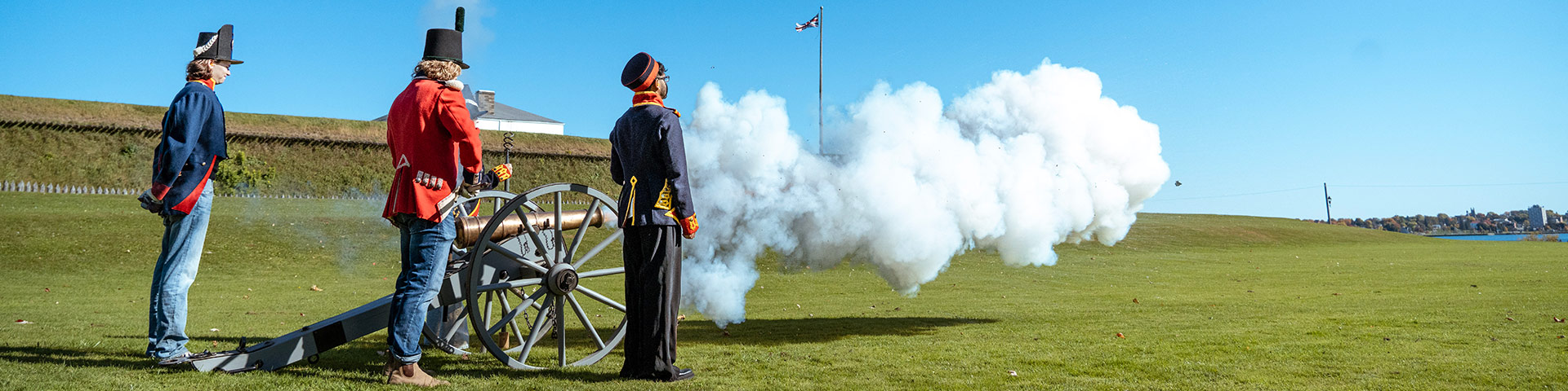 Personnel et un visiteur en costume d'époque posent avec un canon