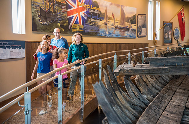 A park staff member shows a family a historic boat