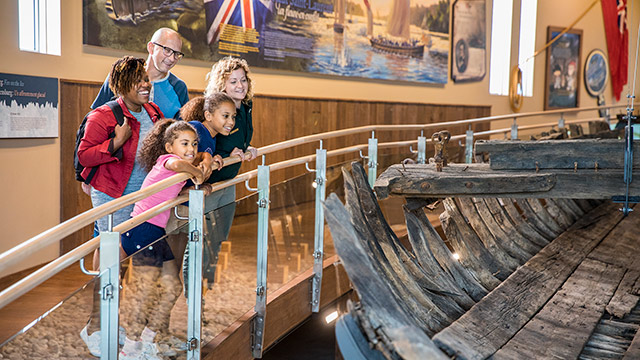 Une famille regarde un bateau historique.