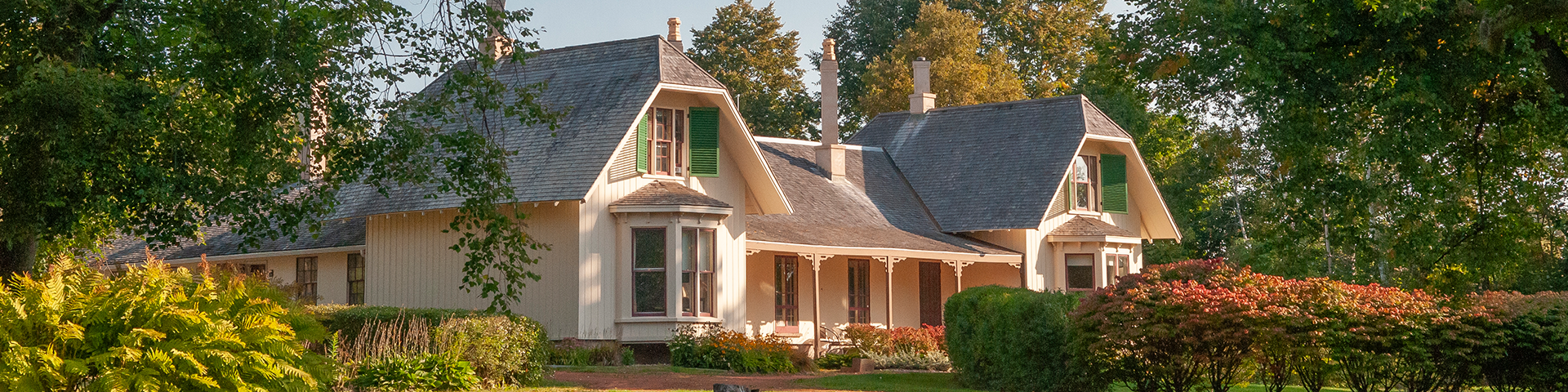 Ardgowan historic home sits amongst many green trees. Sun is shining on the house in the early morning.