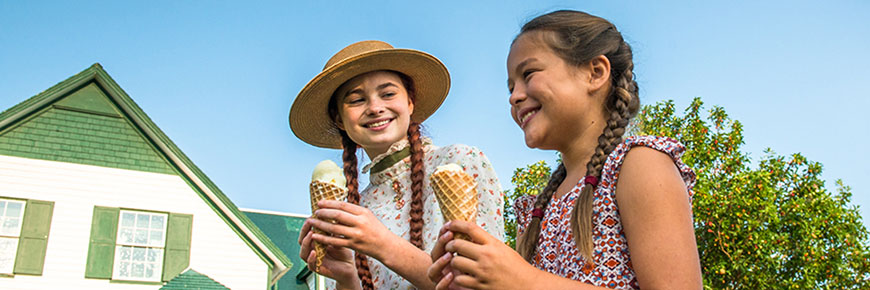Anne impersonator and a young female visitor enjoy ice cream at Green Gables Heritage Place.