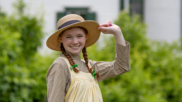 A young girl wearing a yellow dress and straw hat.