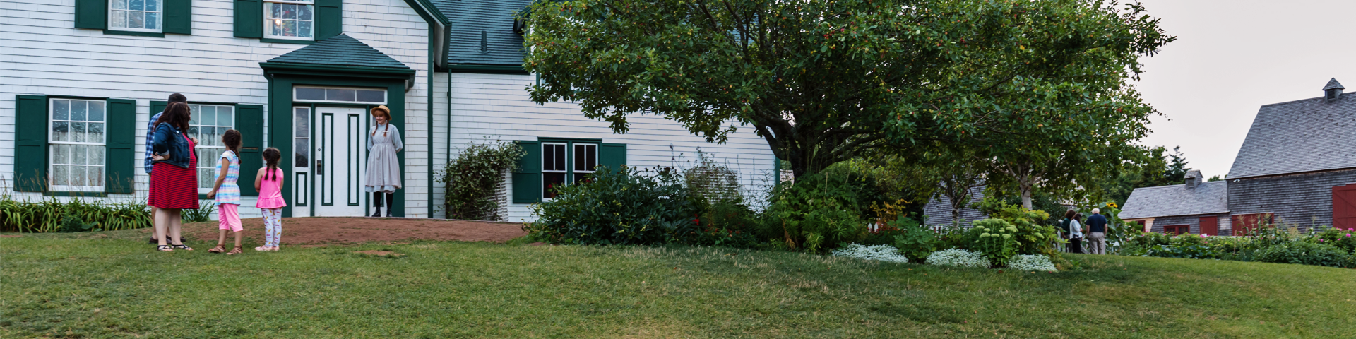 Anne se tient devant la Maison aux pignons verts pour accueillir les visiteurs.