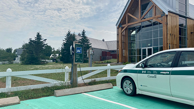 A Parks Canada vehicle is parked at an EV charger outside of Green Gables Visitor information centre.
