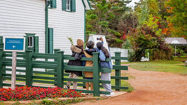 Three visitors take a selfie on the ramp at the back of Green Gables house. 