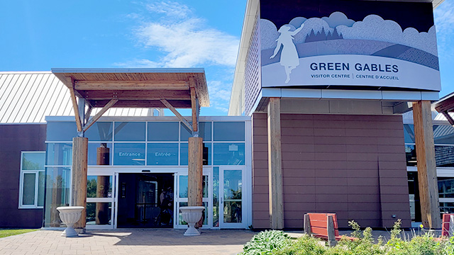 The main entrance to the Visitor Information Centre at Green Gables Heritage Place. There is large columns that span across the door way and a large sign. 