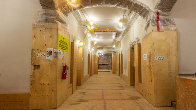 a long hallways with arched ceilings and plywood over the pillars and floors.